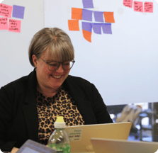 Smiling photograph of Tumelo team member working in the office on her laptop.